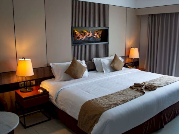 A cozy hotel room with a large bed, decorative pillows, two bedside lamps, and curtains, creating a warm and inviting atmosphere.