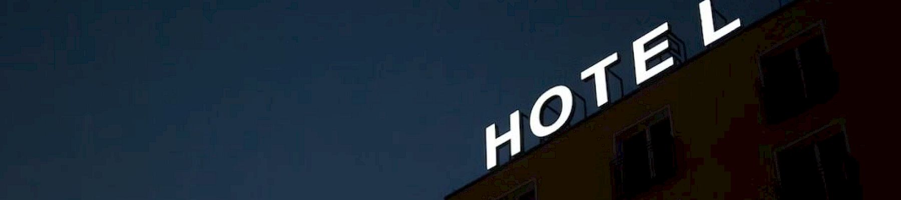 A building with a bright "HOTEL" sign on the rooftop against a dark sky is visible.