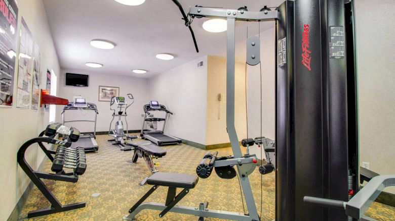 This image shows a gym with various fitness equipment, including treadmills, exercise bikes, and a multi-station workout machine.