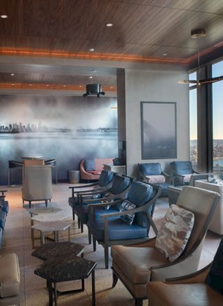The image shows a modern lounge area with stylish seating, a large window with a scenic view, and contemporary decor elements.